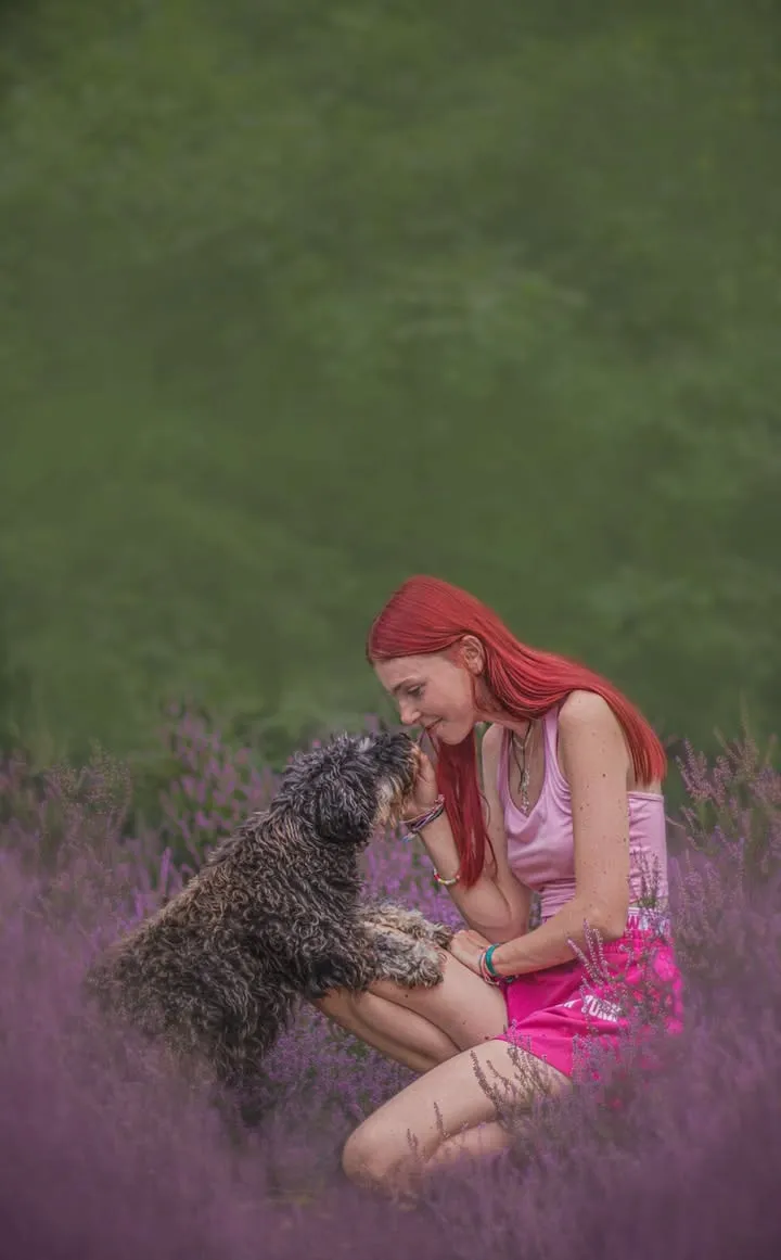 Candice fait un câlin à un chien au milieu de la bruyère.